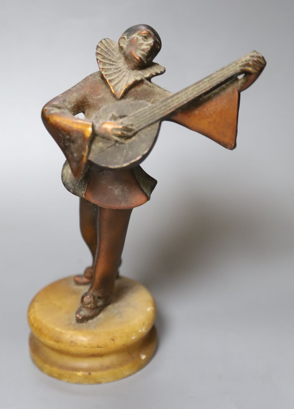 A 1930s Pierrot musician playing the lute, on alabaster plinth, height 23cm